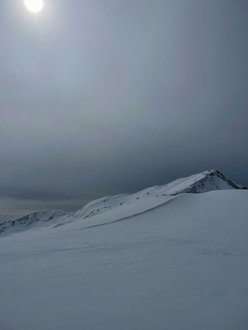 the sun is shining over a snowy mountain