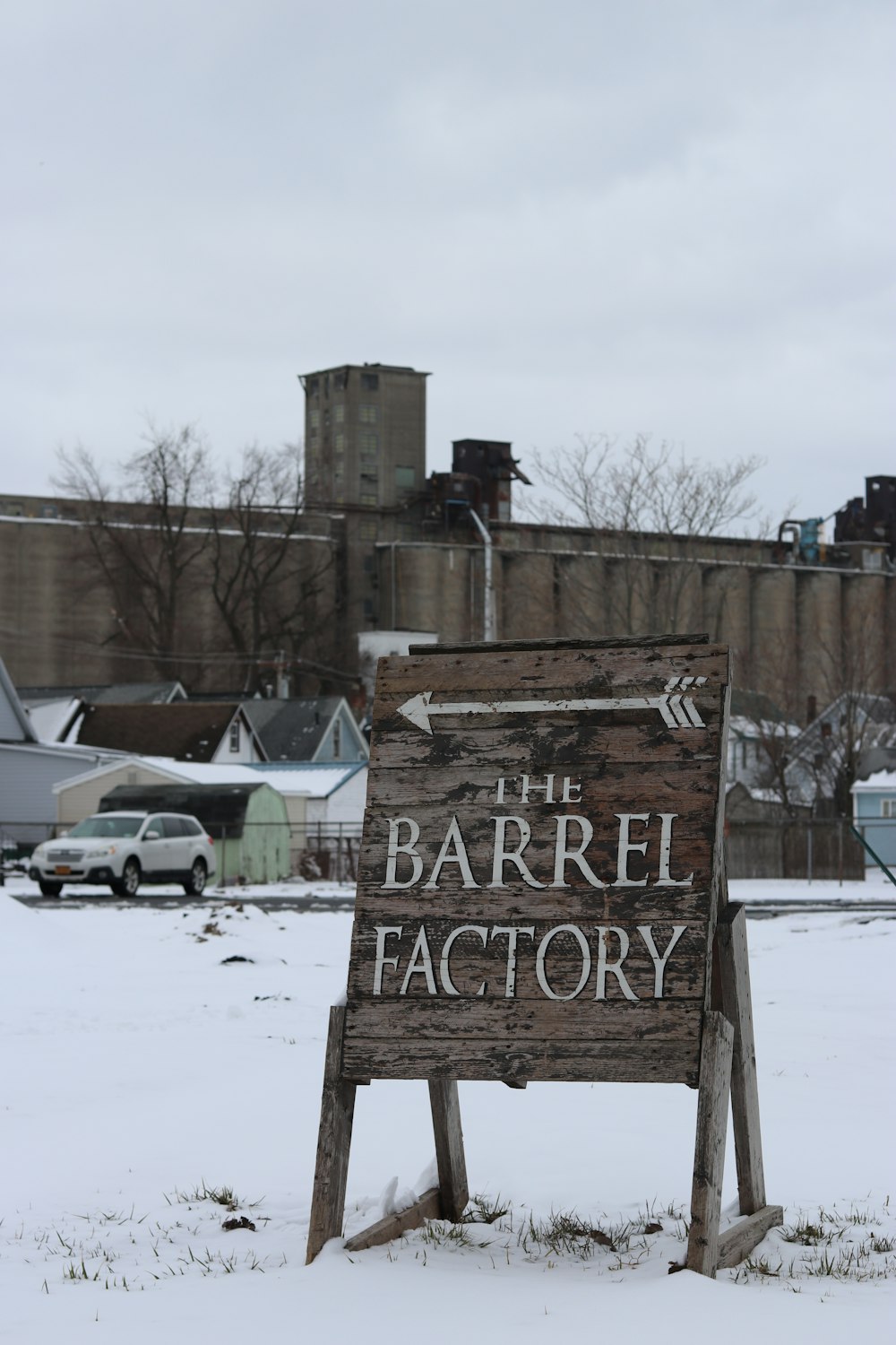 a wooden sign sitting in the middle of a snow covered field