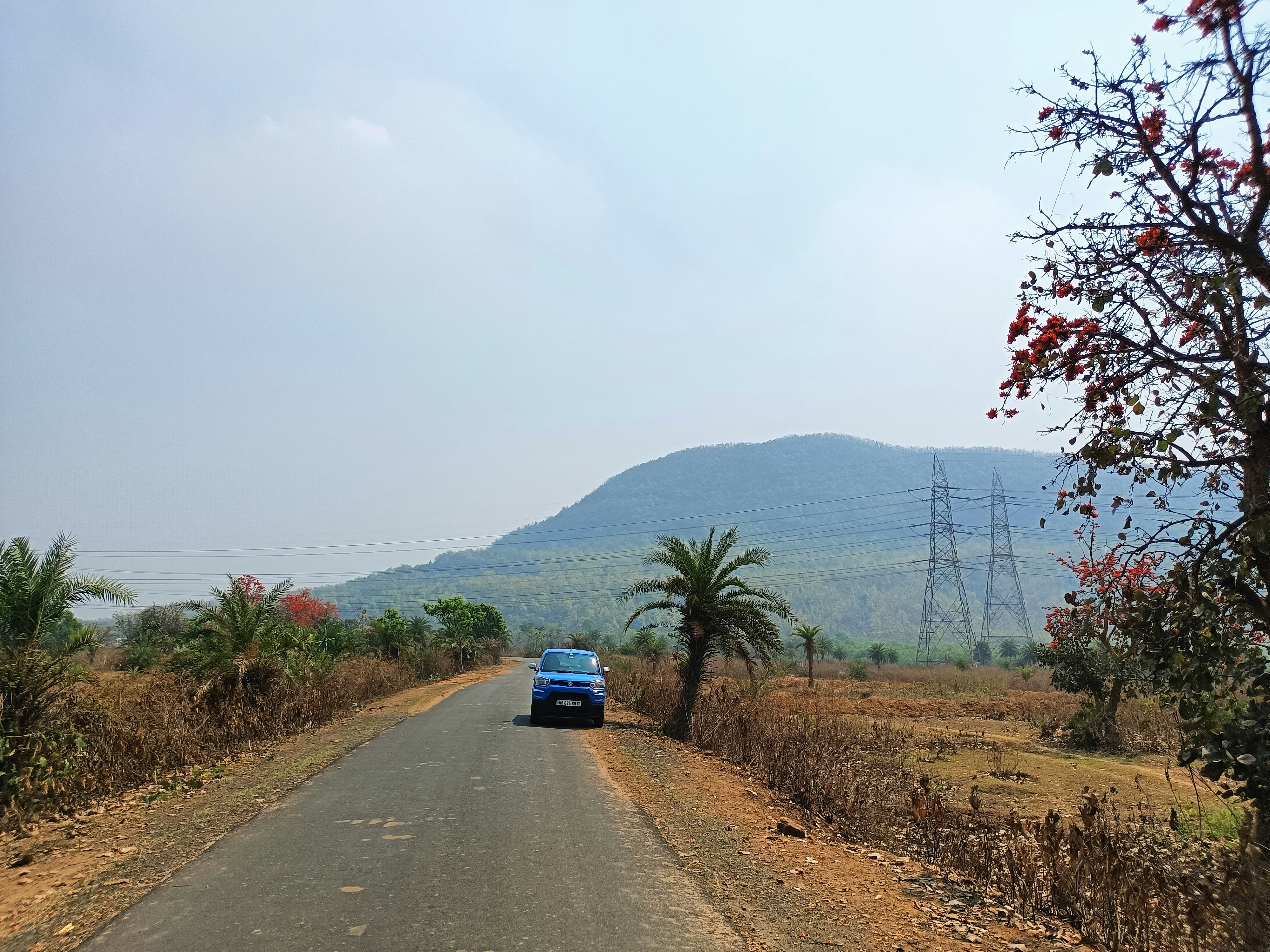 a blue car driving down a rural road
