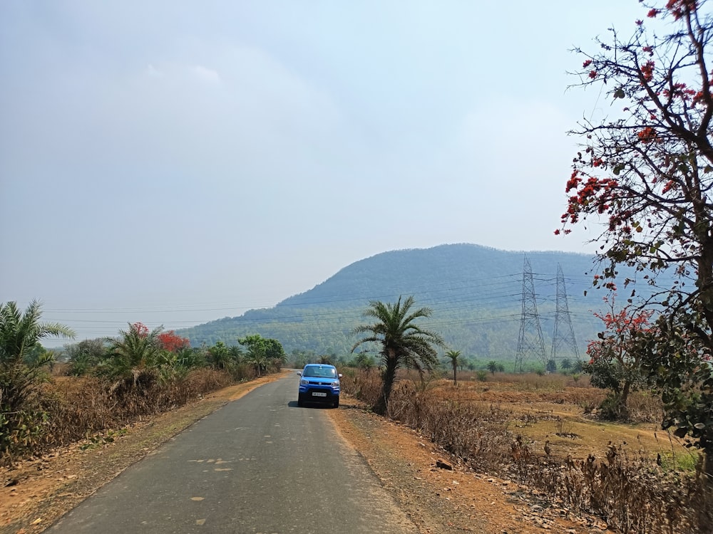 a blue car driving down a rural road