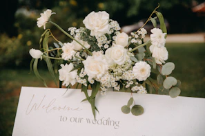 Chic white plinths adorned with fresh florals and a custom welcome sign for a baby shower celebration