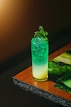 a green and yellow drink sitting on top of a wooden table