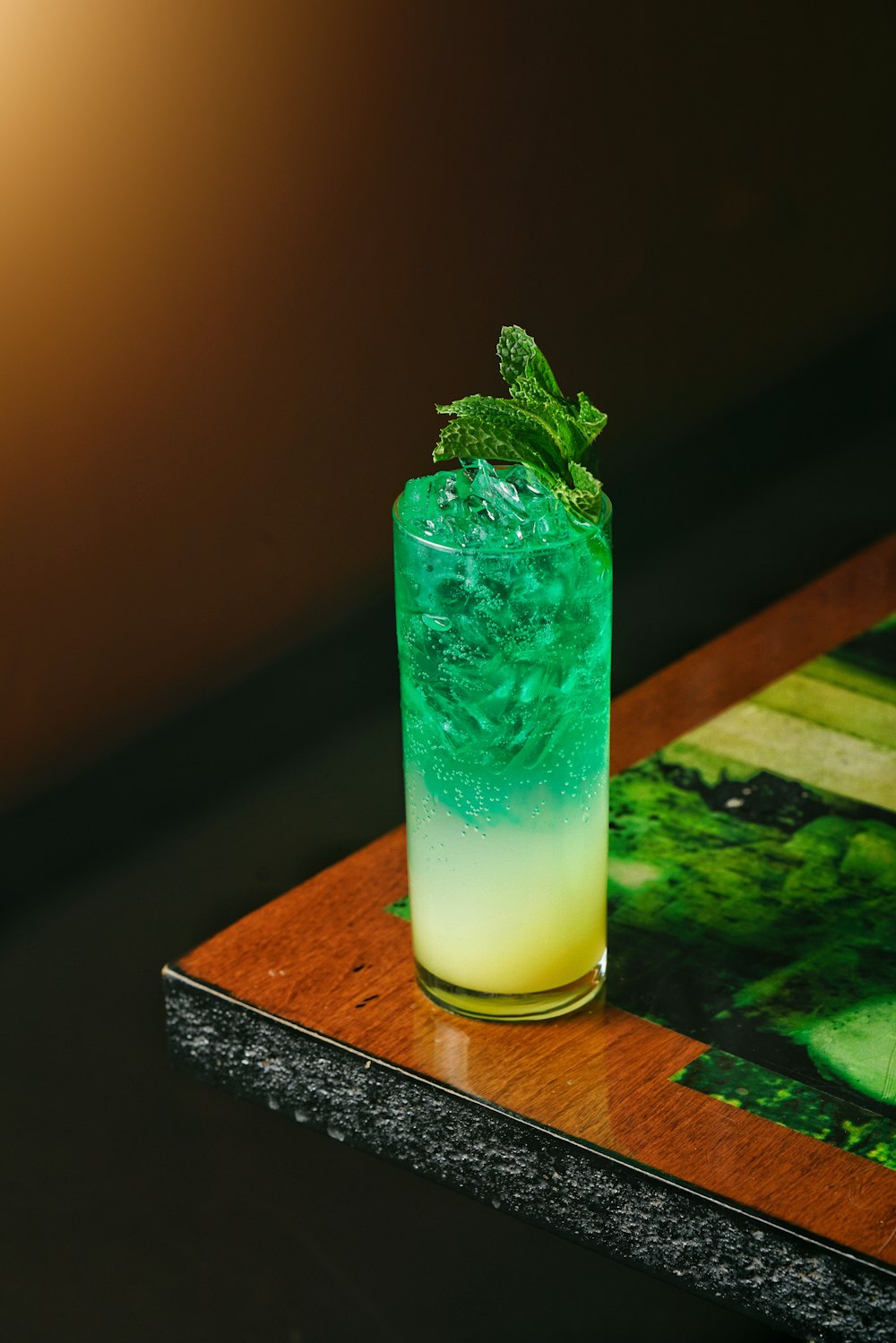 a green and yellow drink sitting on top of a wooden table
