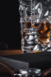 Close-up of a stylish keychain holding a tiny glass vial filled with Ibiza sand, resting on a white minimalist background.