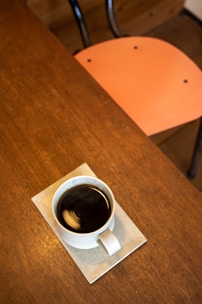 A steaming cup of dark roast coffee on a minimalist wooden table.