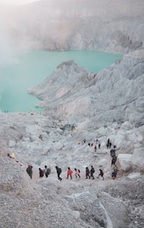 a group of people walking up a hill next to a lake