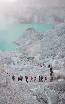 a group of people walking up a hill next to a lake