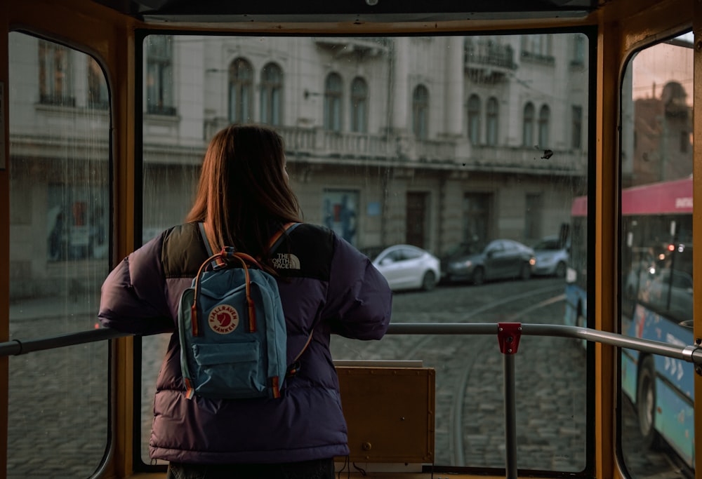 バスの上に立って窓の外を眺める女性
