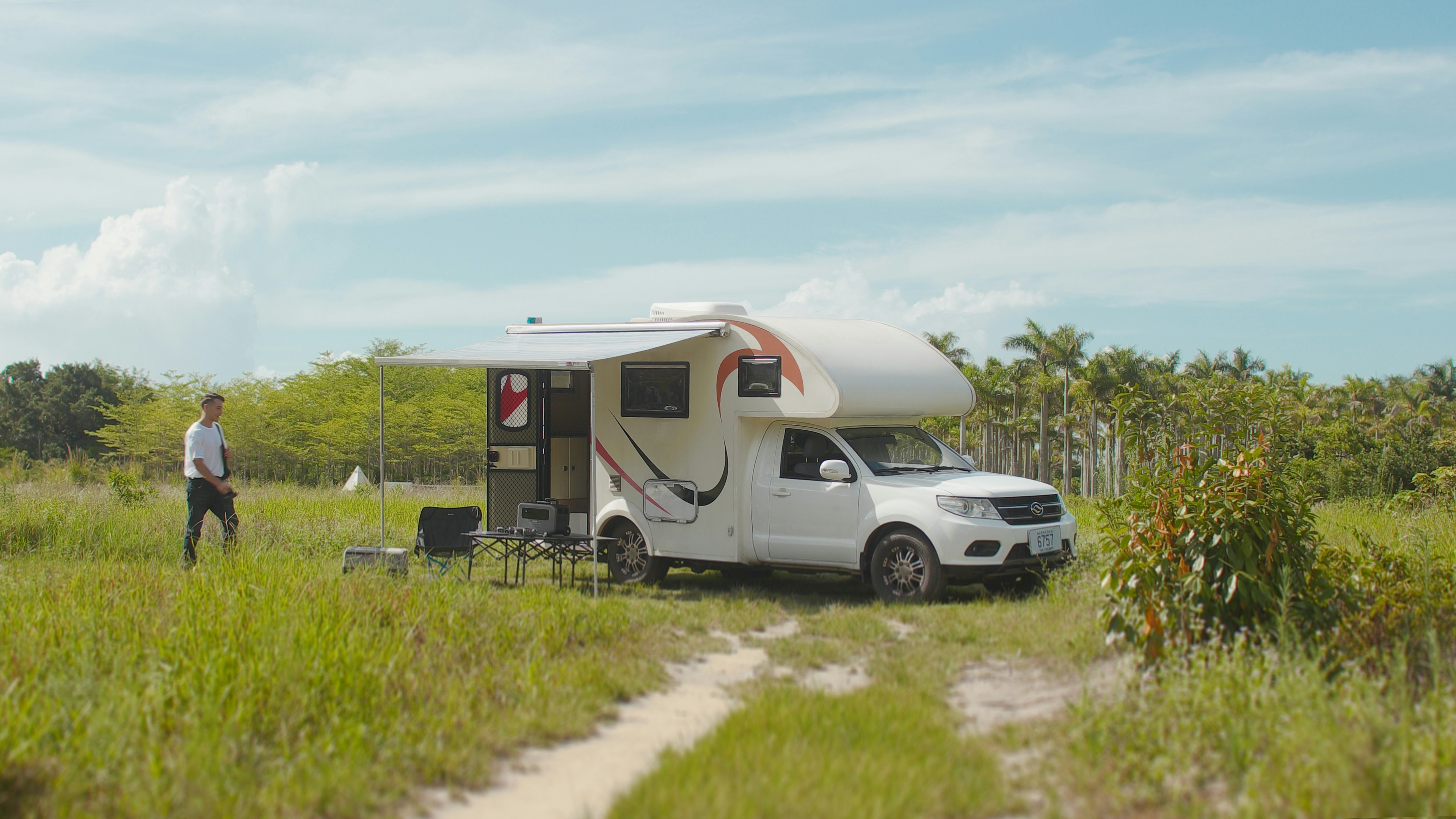 a man standing next to a camper in a field