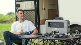 a man sitting besite a bluetti like generator
