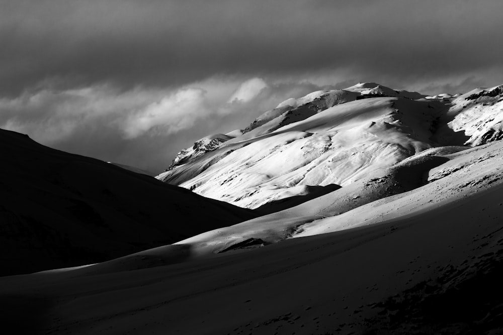 a mountain covered in snow under a cloudy sky