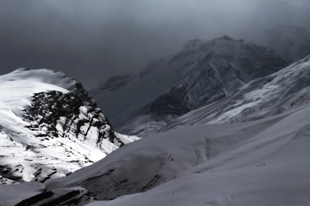 a mountain covered in snow under a cloudy sky