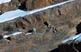 A mother snow leopard with her cub nestled among alpine rocks.