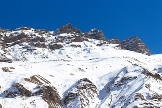 a large mountain covered in snow under a blue sky