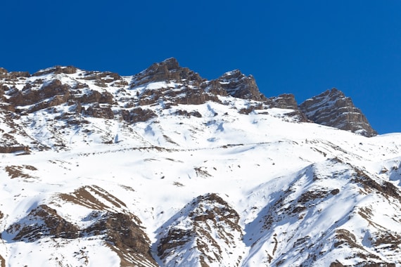 a large mountain covered in snow under a blue sky