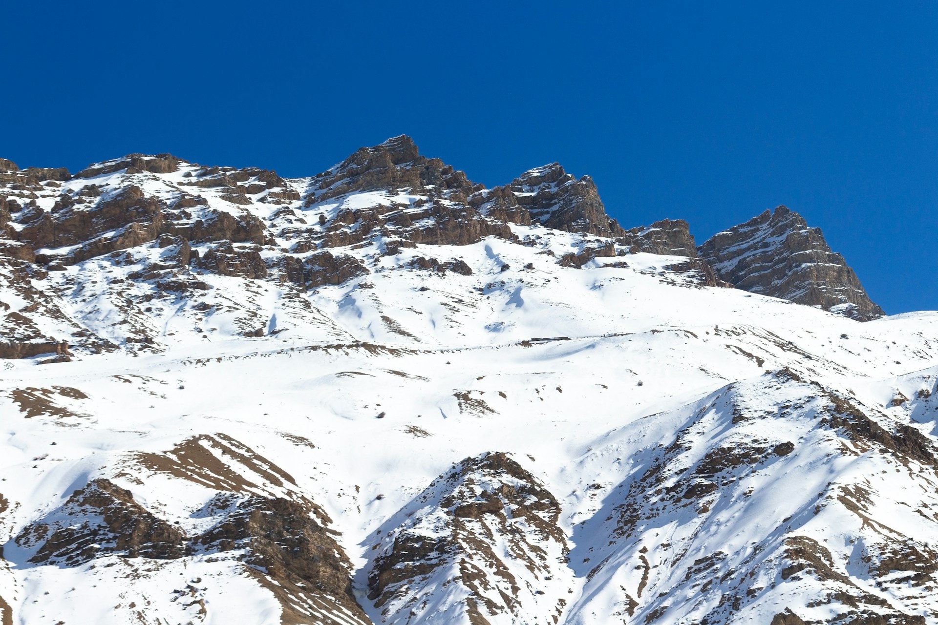 a large mountain covered in snow under a blue sky