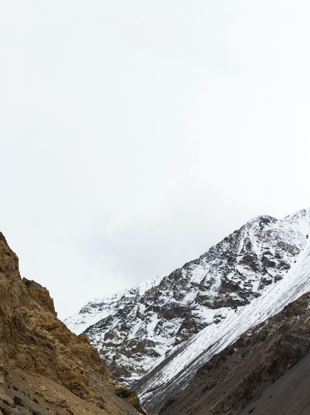 a man standing on top of a mountain next to a snow covered mountain