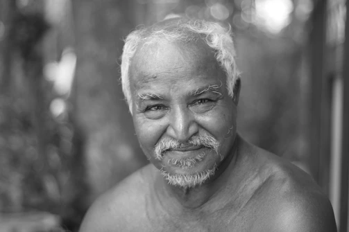 Portrait of an elderly man smiling softly in soft light.
