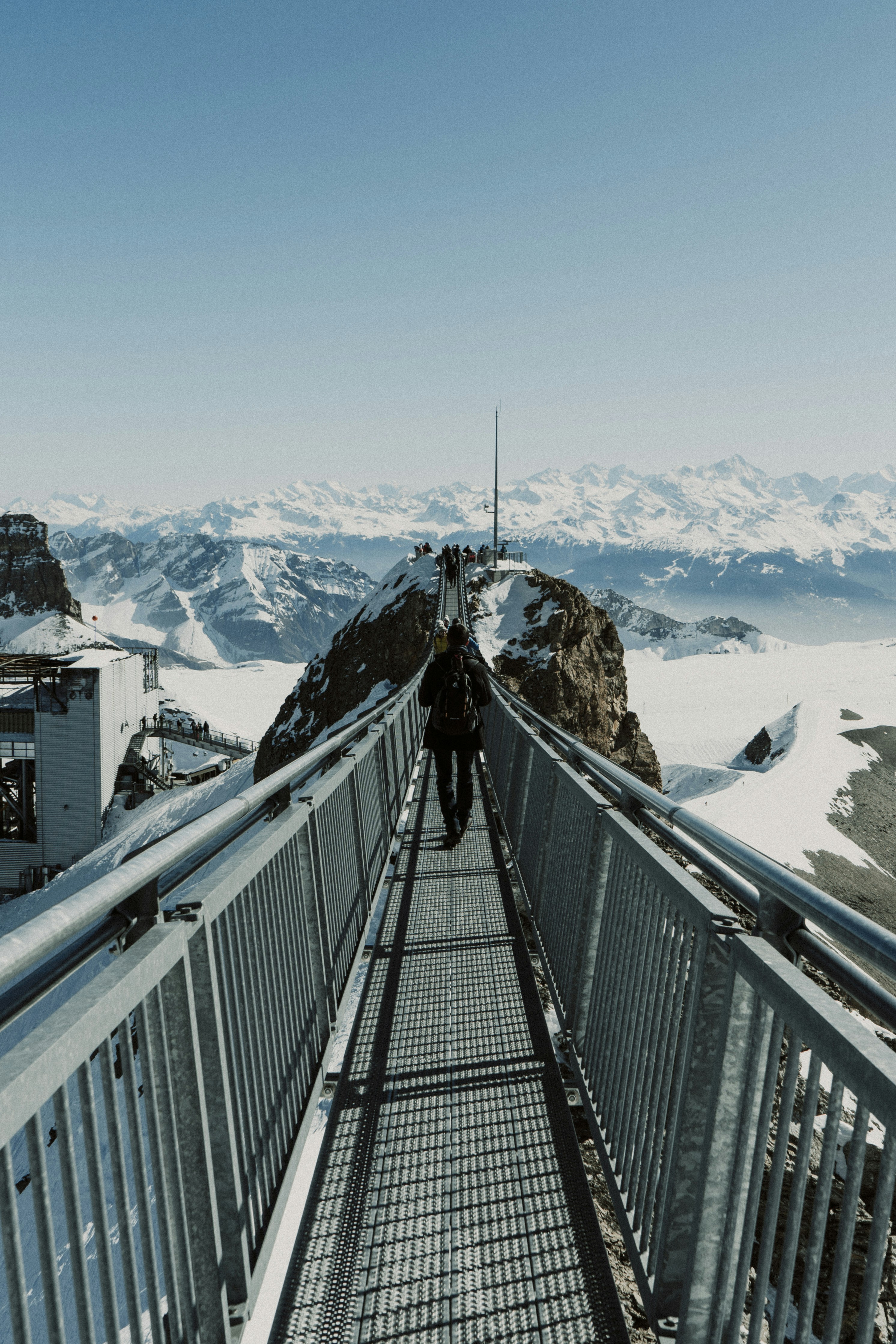Un homme traversant un pont au-dessus d’une montagne enneigée