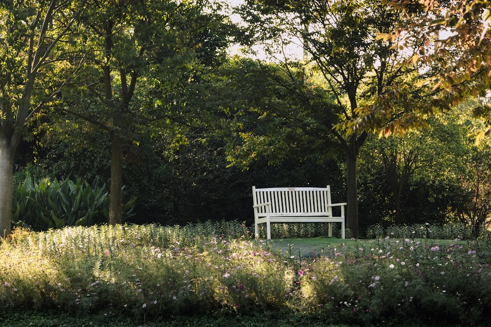 a white bench sitting in the middle of a park