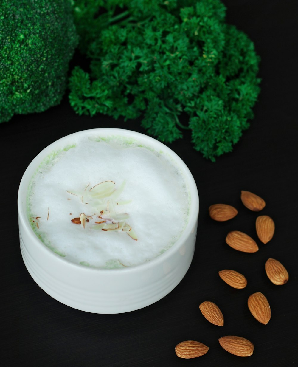 a white container filled with almonds next to broccoli