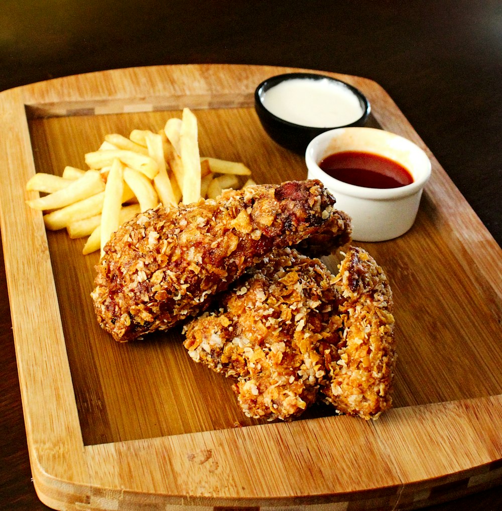 un vassoio di legno condito con pollo fritto e patatine fritte