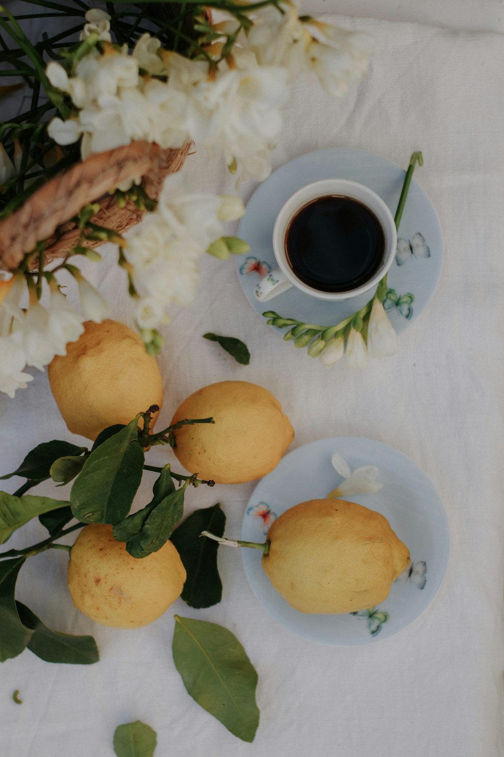 a table topped with plates of lemons and a cup of coffee