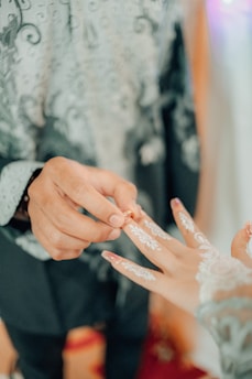 Close-up of hands exchanging wedding rings with a Quran and prayer beads nearby.