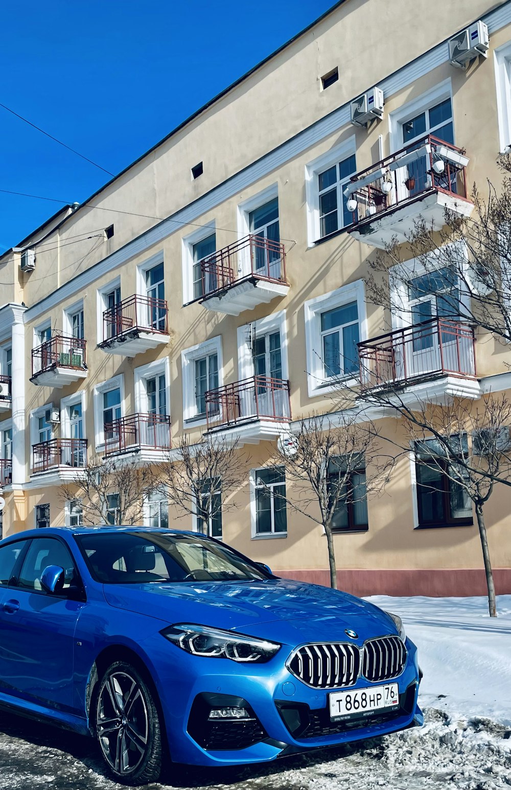 a blue bmw car parked in front of a building