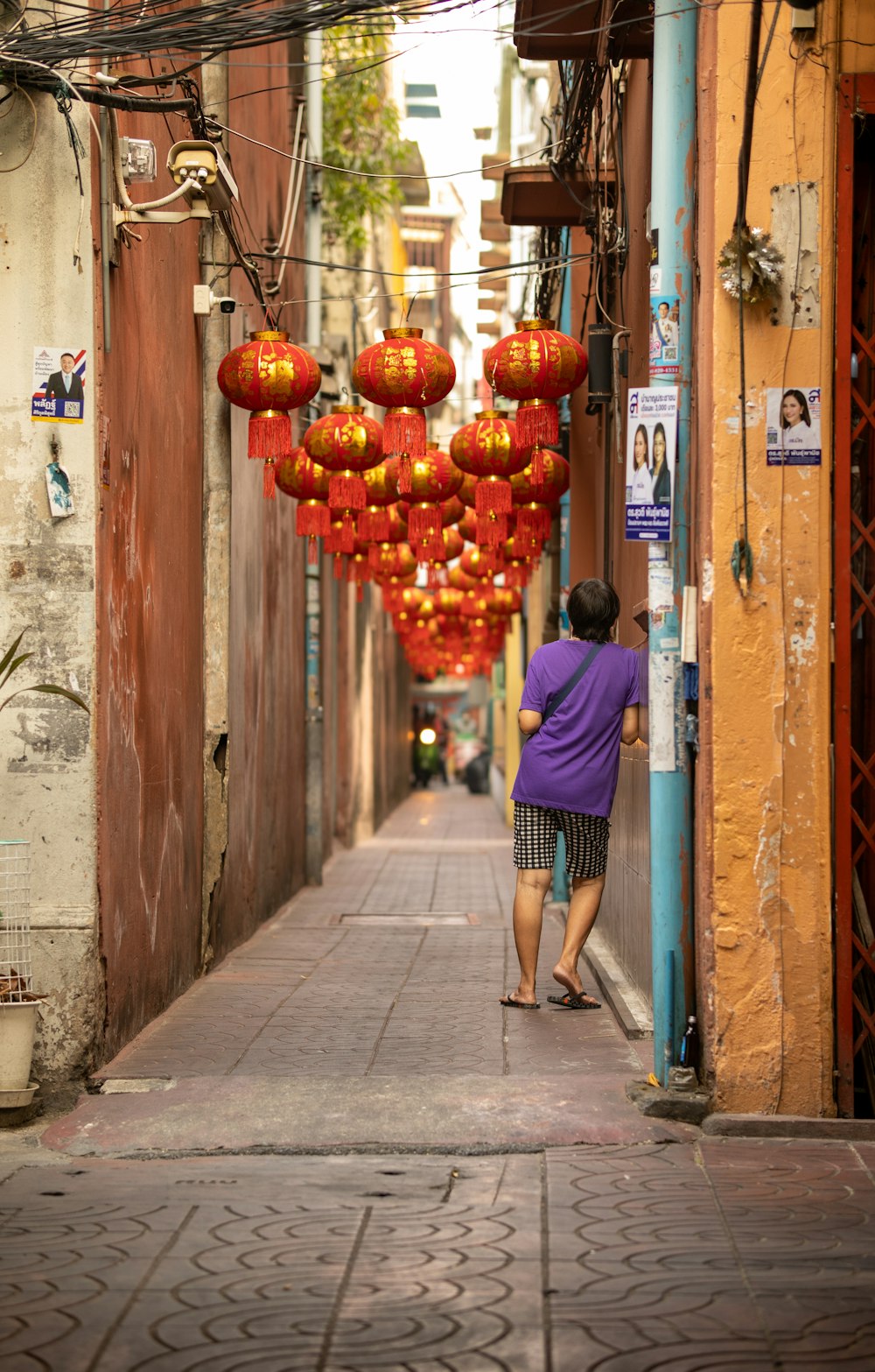 a woman walking down a street under red lanterns