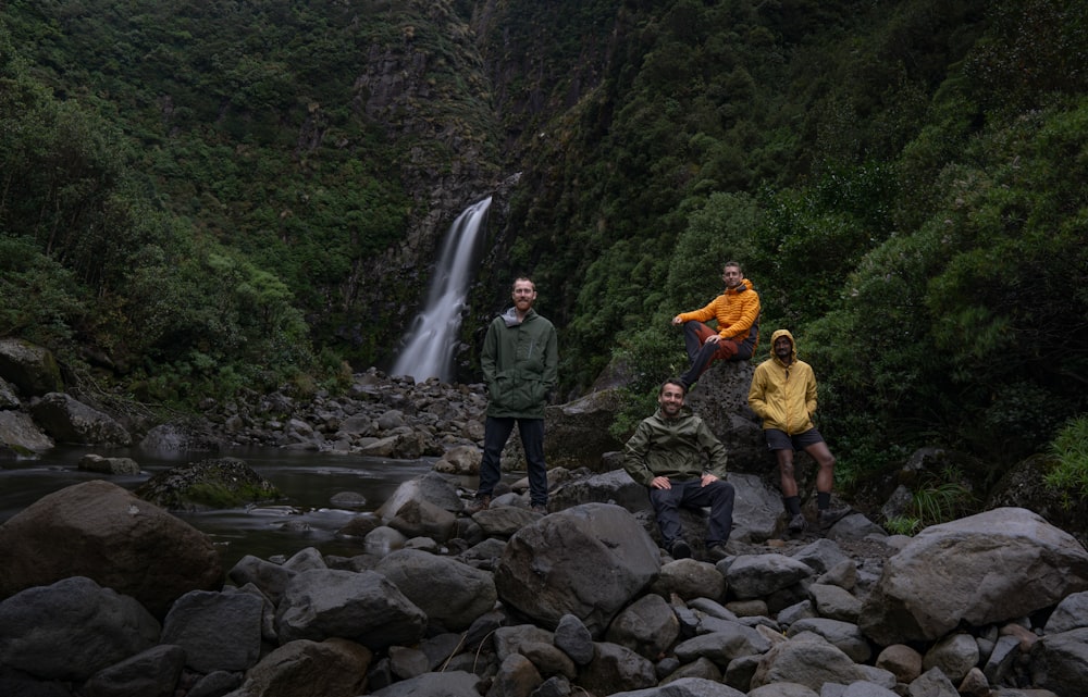 Eine Gruppe von Menschen steht auf Felsen vor einem Wasserfall