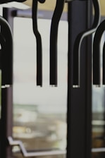 Suspended black lighting fixtures with multiple curved arms are prominently in focus. The background features large glass windows with blurred views, providing natural light.