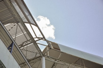 Close-up of a sleek steel frame structure of a garden shed under a bright blue sky.