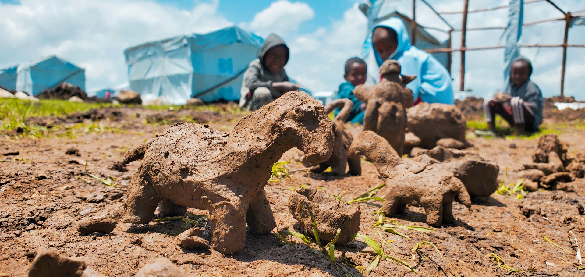 A group of kids proudly displaying their clay sculptures on a wooden table, smiling with excitement.
