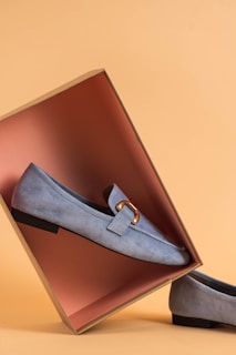 A close-up of a pair of shoes in a rich blue shade resting on a neutral background.