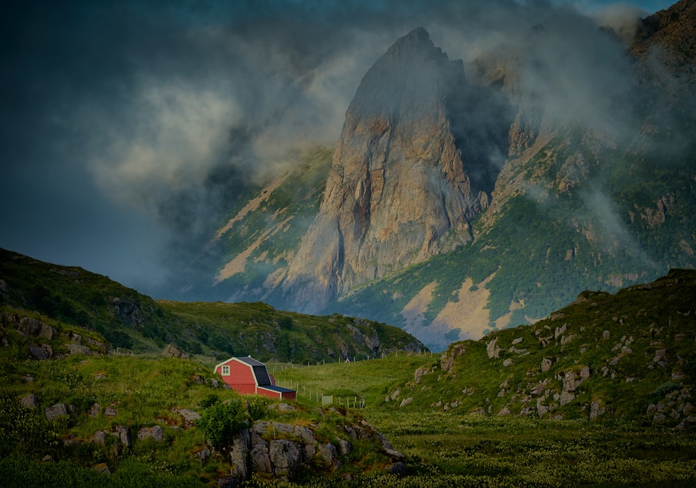 a red barn in the middle of a mountain range