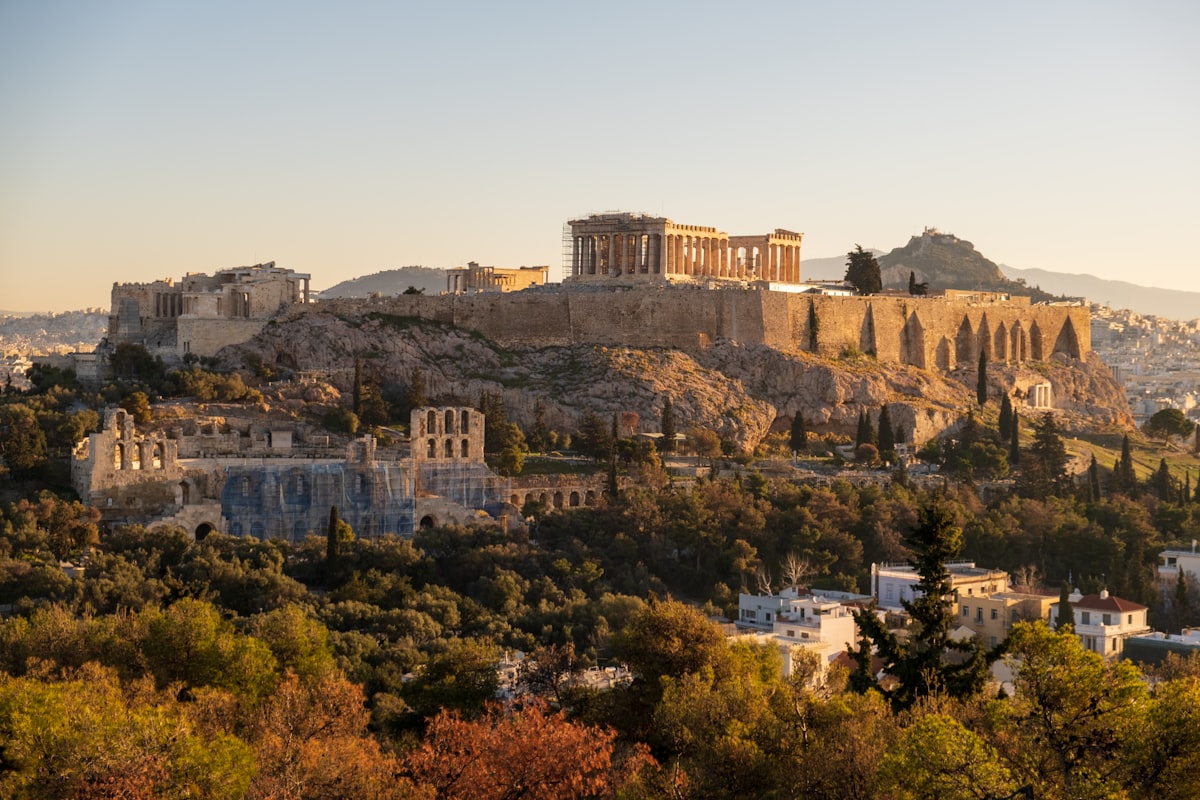 Athens May — the Acropolis glowing in warm golden sunset light above the city in peak spring