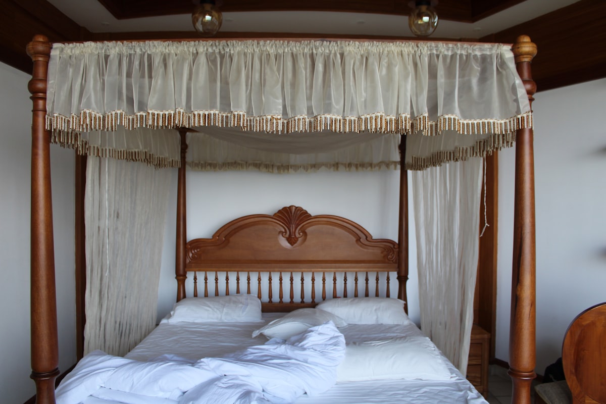 A serene Indian bedroom with a canopy bed and warm light — the kind of room a Haridwar stay should feel like