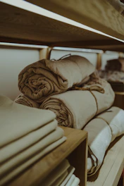a stack of folded towels sitting on top of a wooden shelf