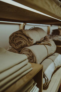 a stack of folded towels sitting on top of a wooden shelf