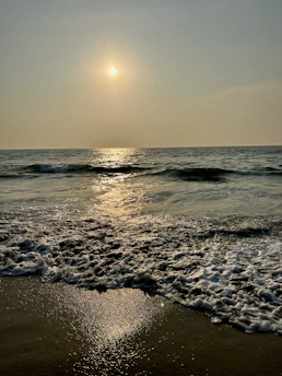 A serene view of Nishkalank Mahadev temple at sunset, with gentle waves reflecting the golden light.