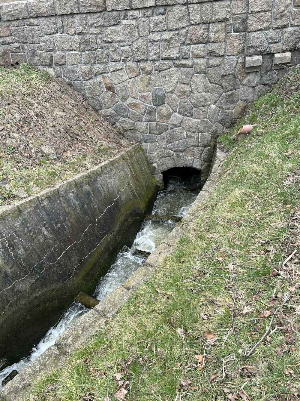 un piccolo ruscello che scorre sotto un ponte di pietra