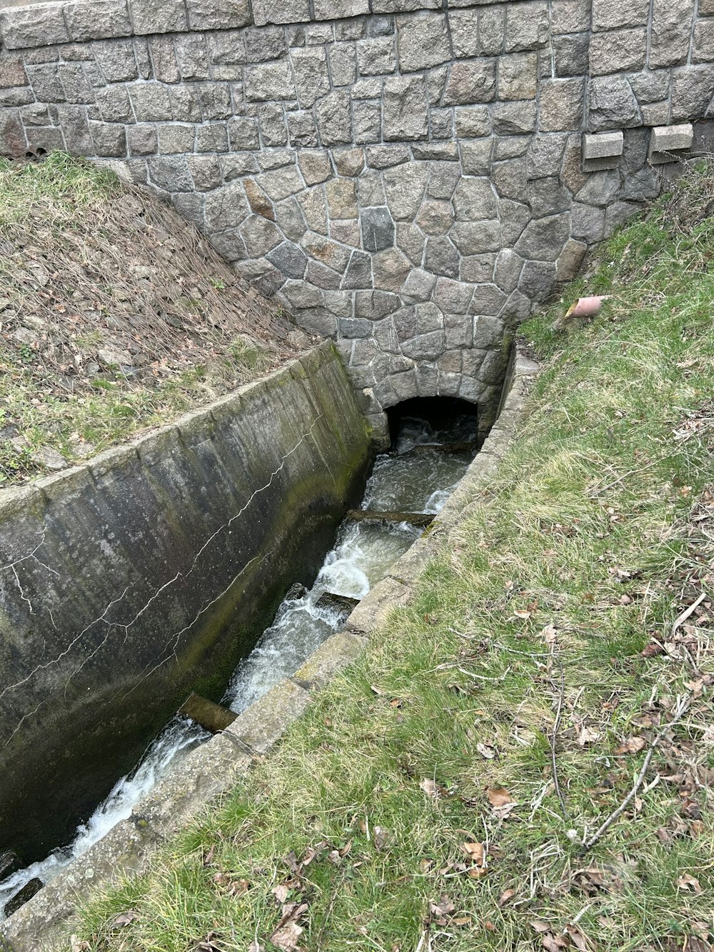 a small stream running under a stone bridge
