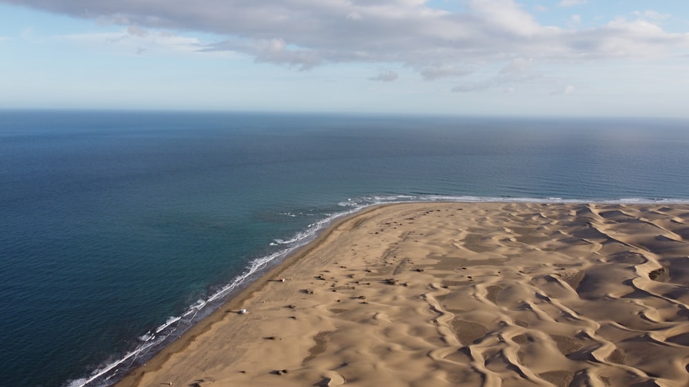 a sandy beach next to the ocean under a cloudy sky