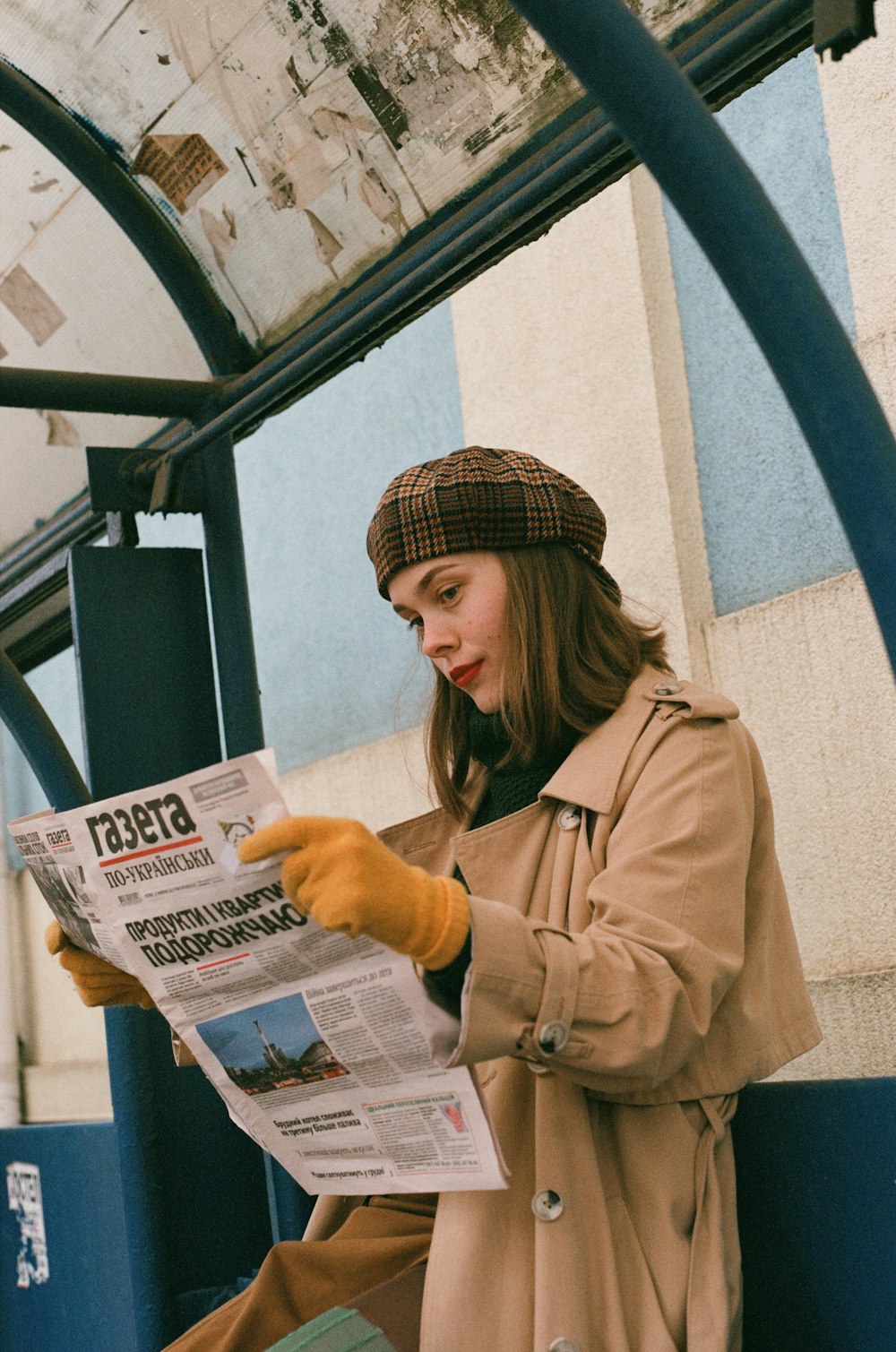 a woman reading a newspaper while sitting on a bench