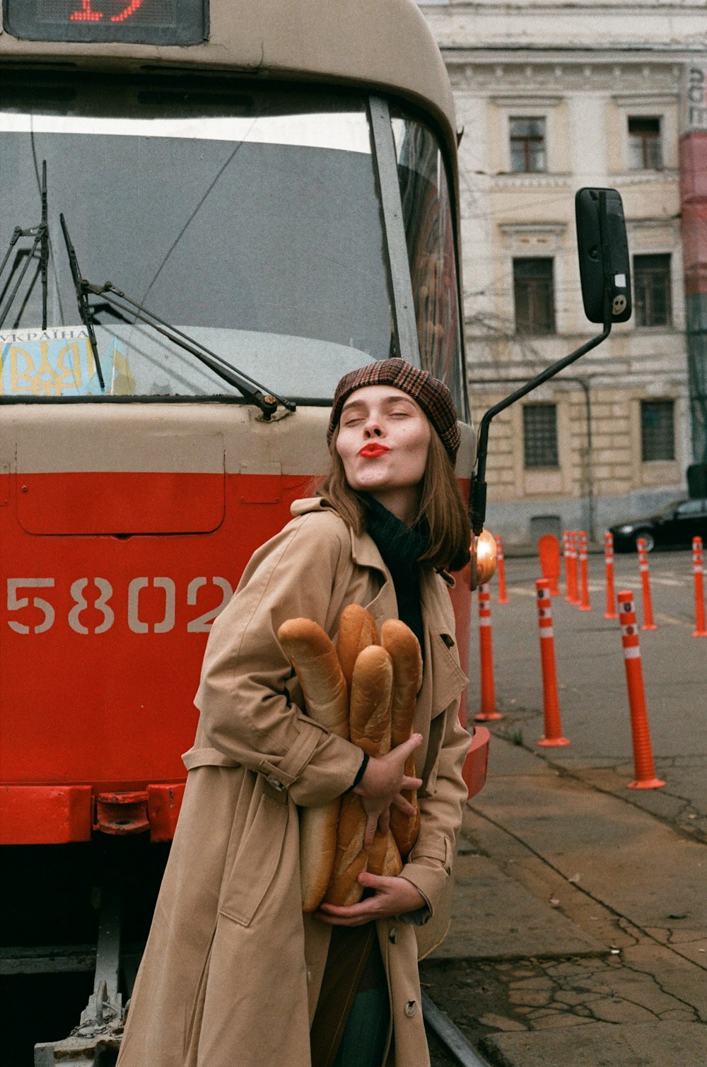 a woman in a trench coat holding a teddy bear