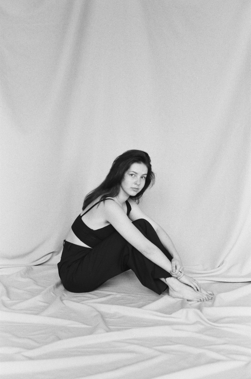 a black and white photo of a woman sitting on a bed