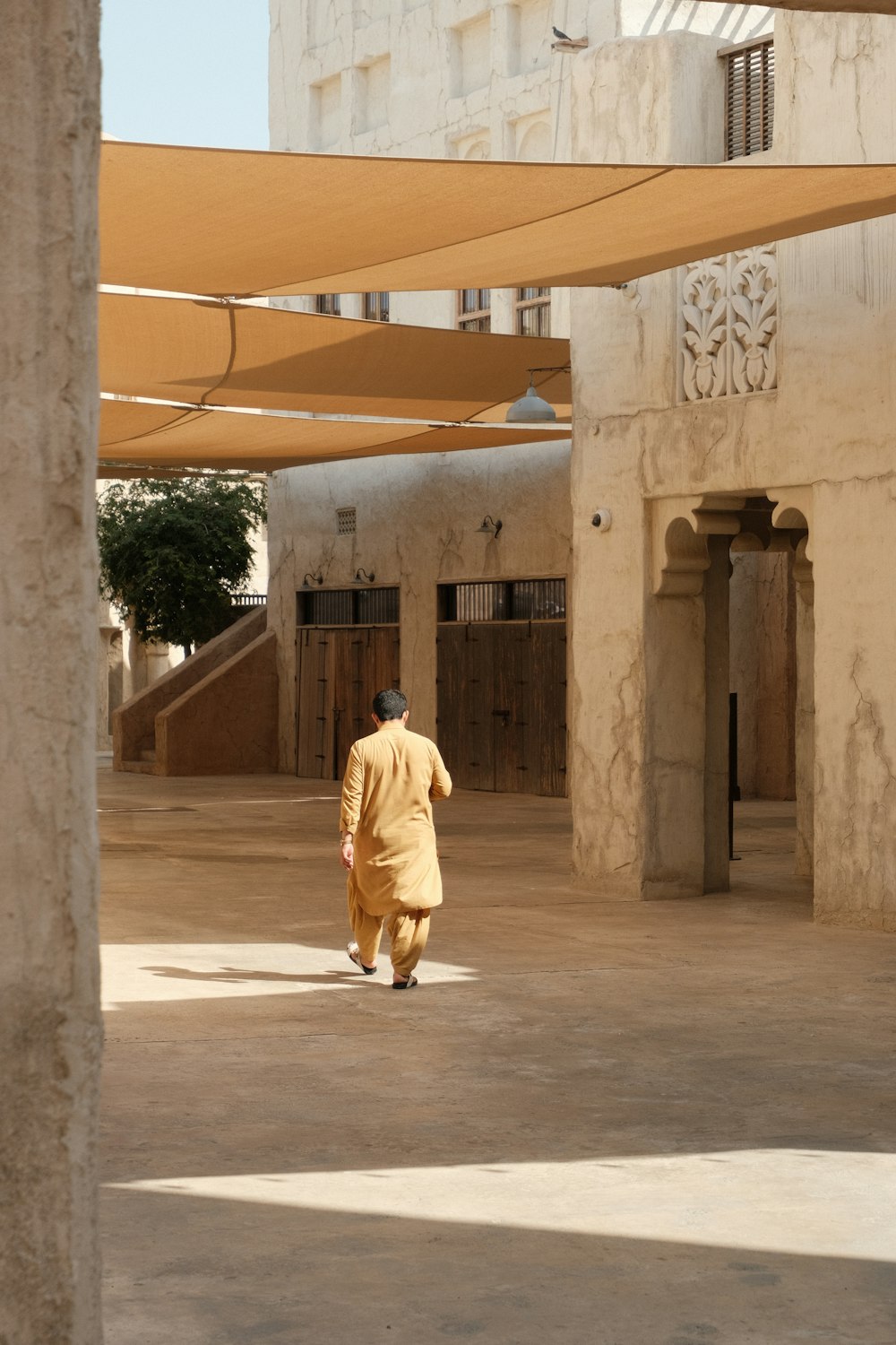a man in a yellow outfit walking in a courtyard