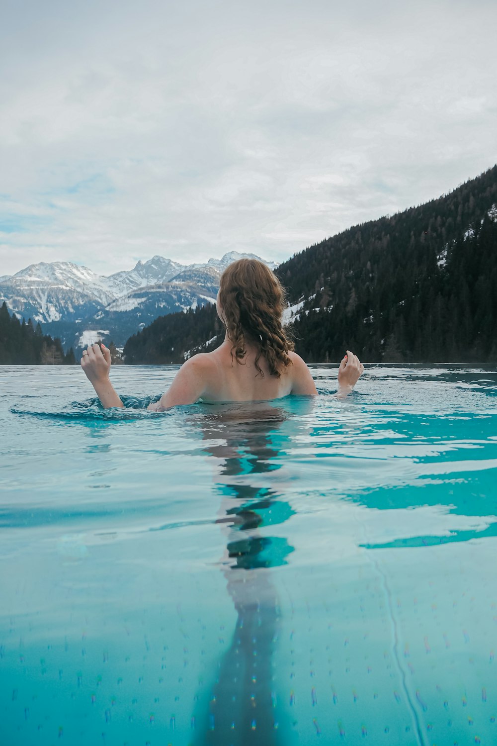 a woman swimming in a pool with mountains in the background