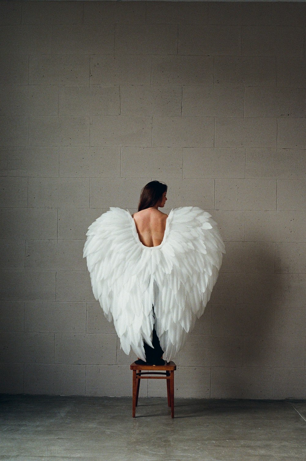 a woman sitting on a chair with white wings on her back
